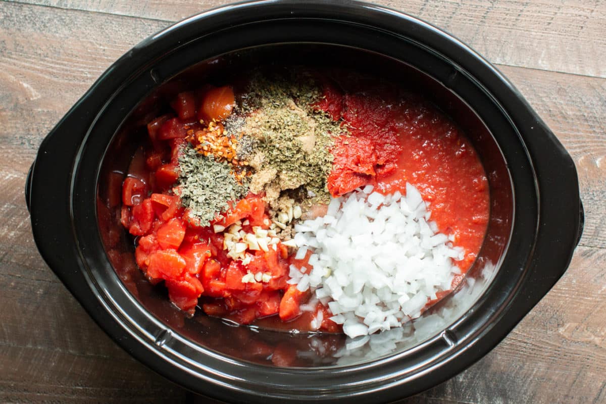 Ingredients for spaghetti sauce in the slow cooker separated in sections.