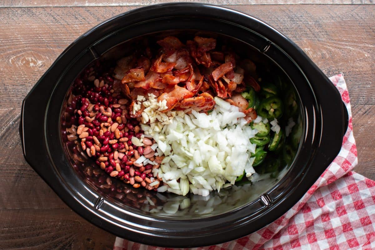 beans, bacon, garlic, onion, jalapeno all separated in the slow cooker.