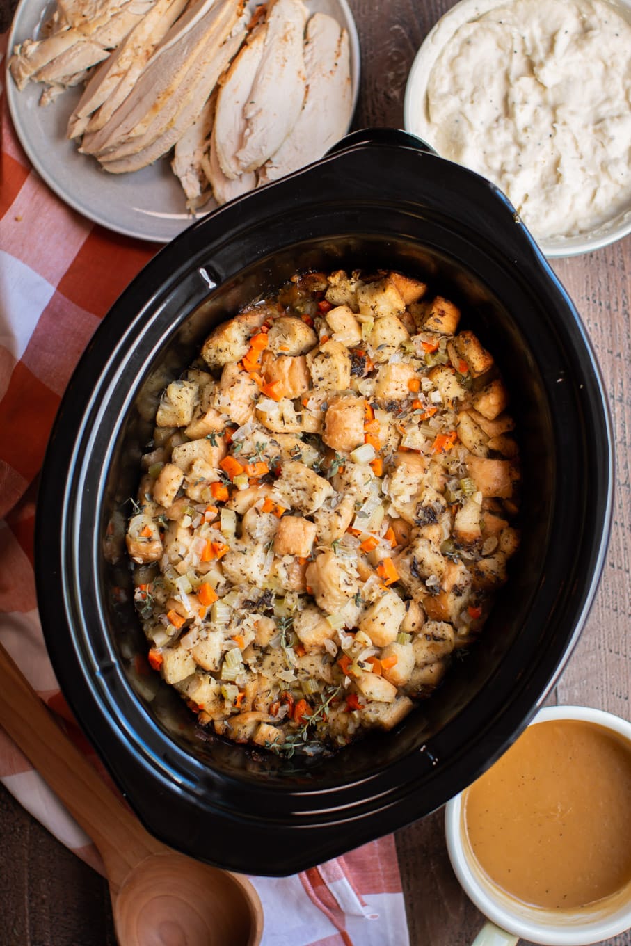 Stuffing done cooking in the slow cooker. Side dishes around the side.
