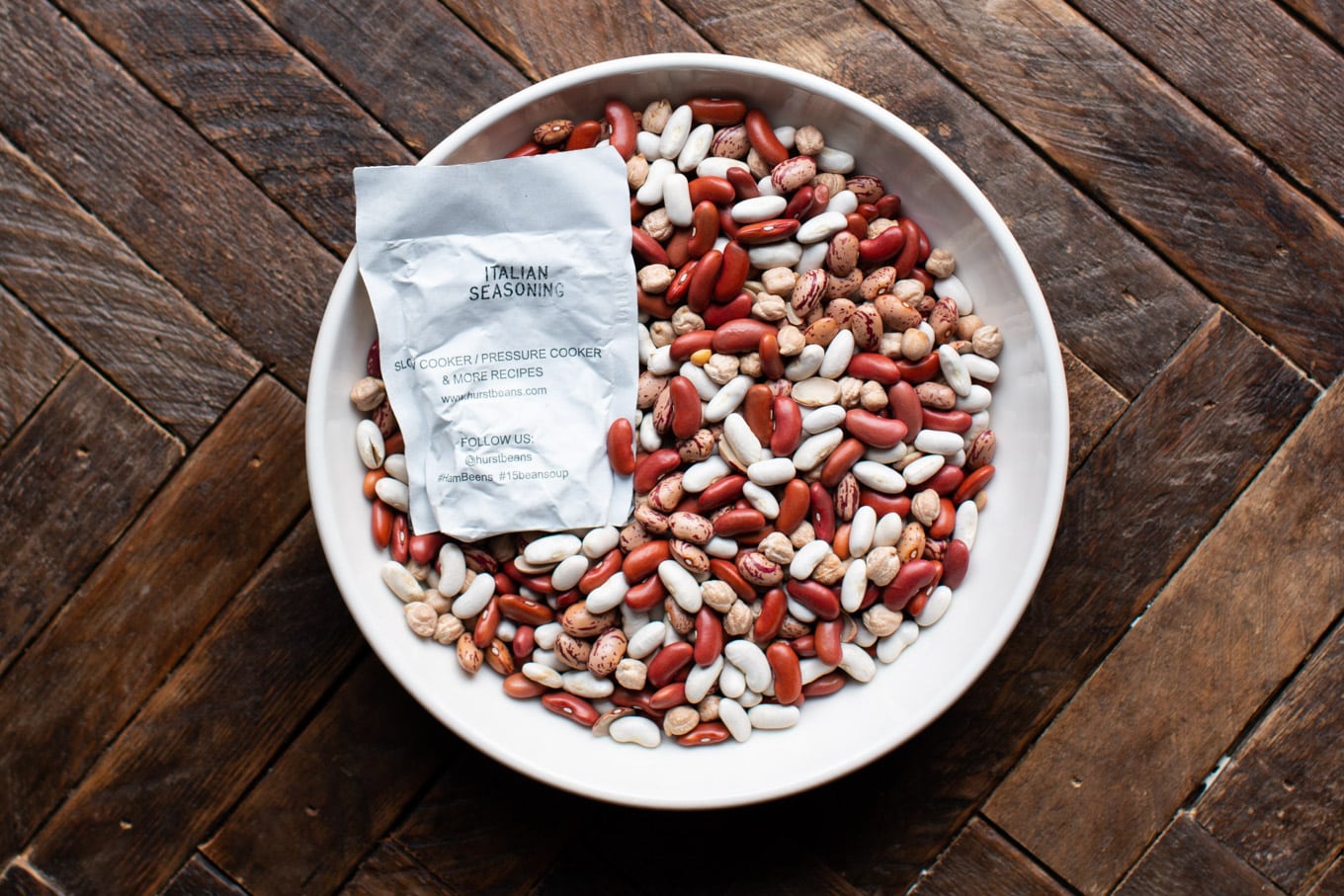 white bowl with red, white and pinto beans, Italian Seasoning packet on top.