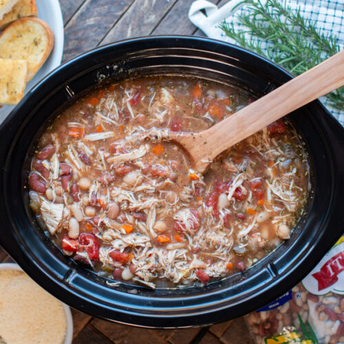 Cooked Italian bean soup with wooden spoon in it.