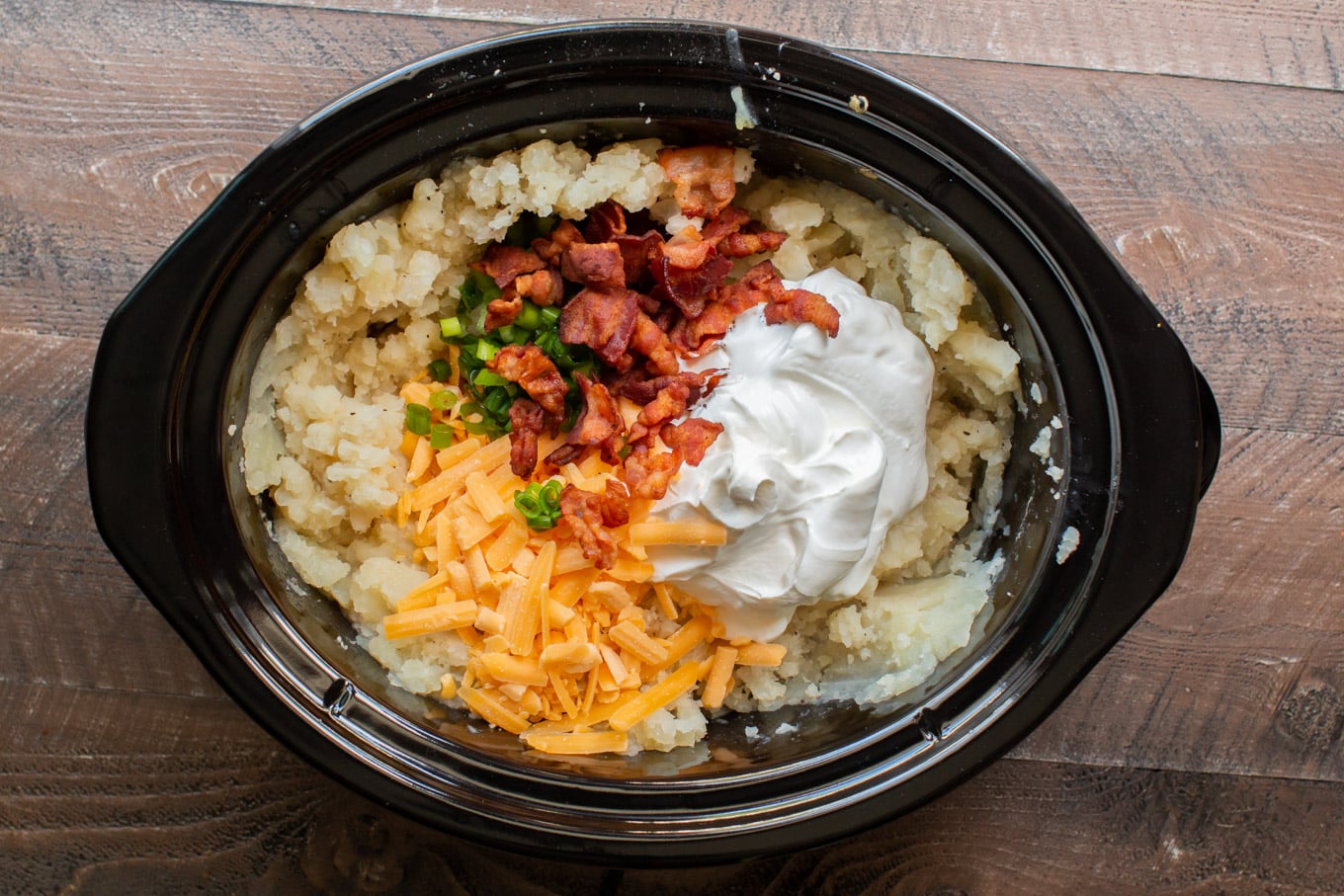 mashed potatoes with sour cream, bacon, green onions and cheese on top.