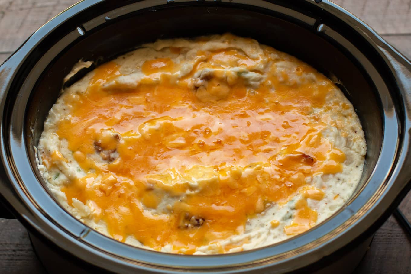 mashed potatoes in slow cooker with cheese on top.