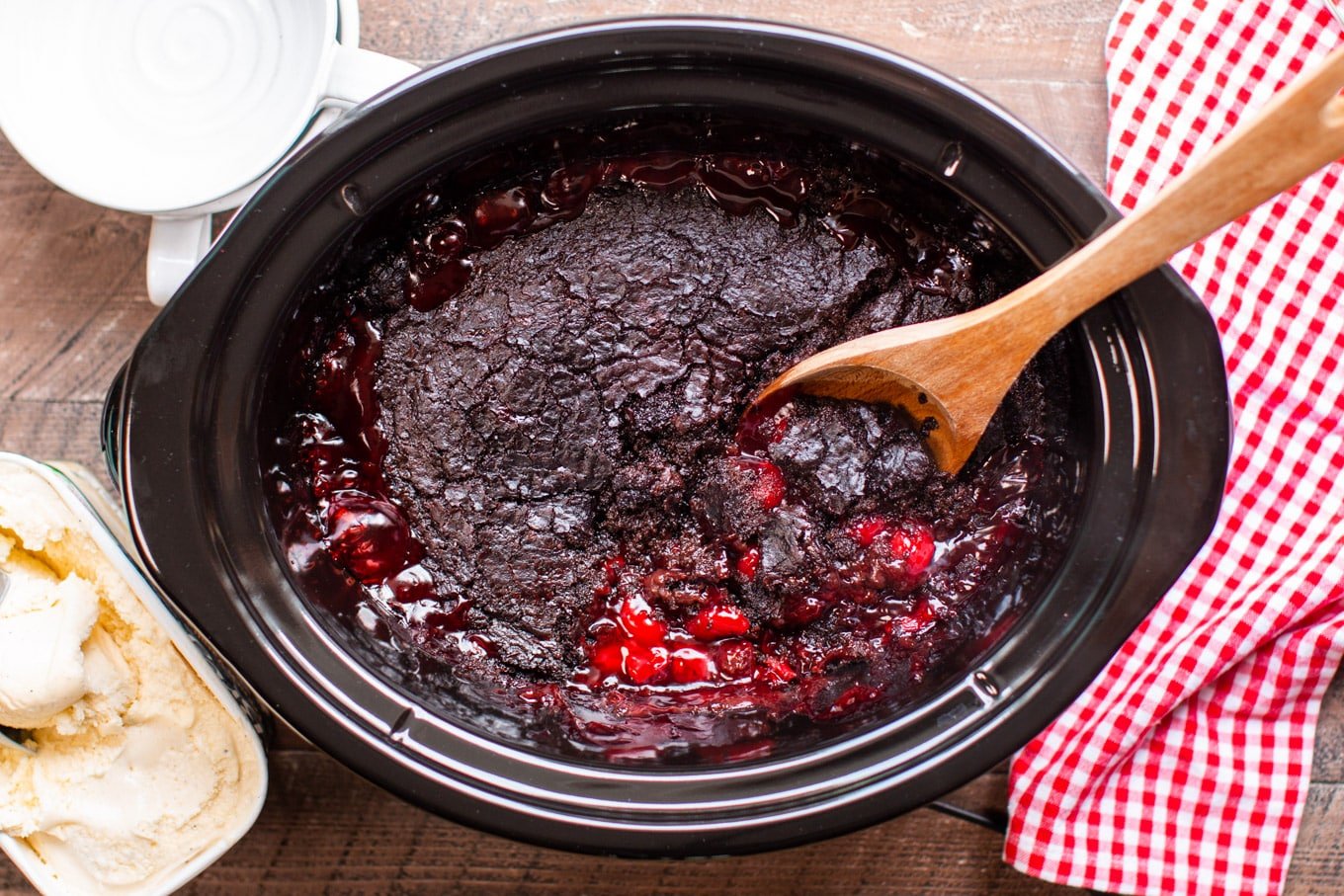 Serving Chocolate Cherry Dump Cake with a wooden spoon