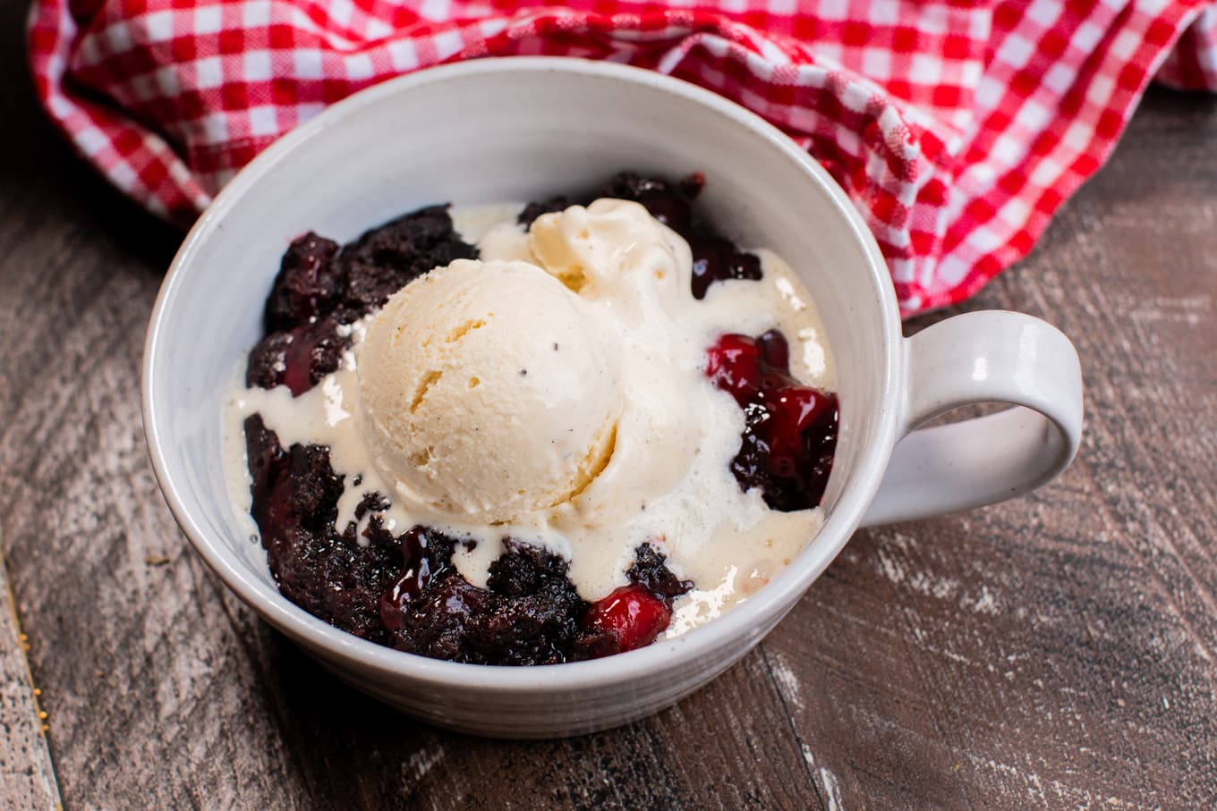 cherry chocolate dump cake in a bowl with ice cream on top