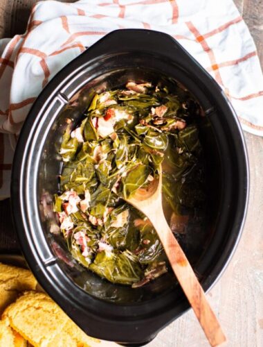 cooked collard green with wooden spoon in the slow cooker.