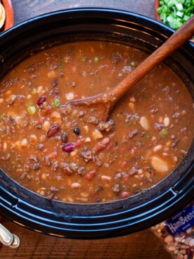 15 bean taco soup with spoon in it, chips and cheese on side