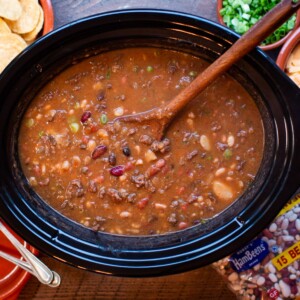15 bean taco soup with spoon in it, chips and cheese on side
