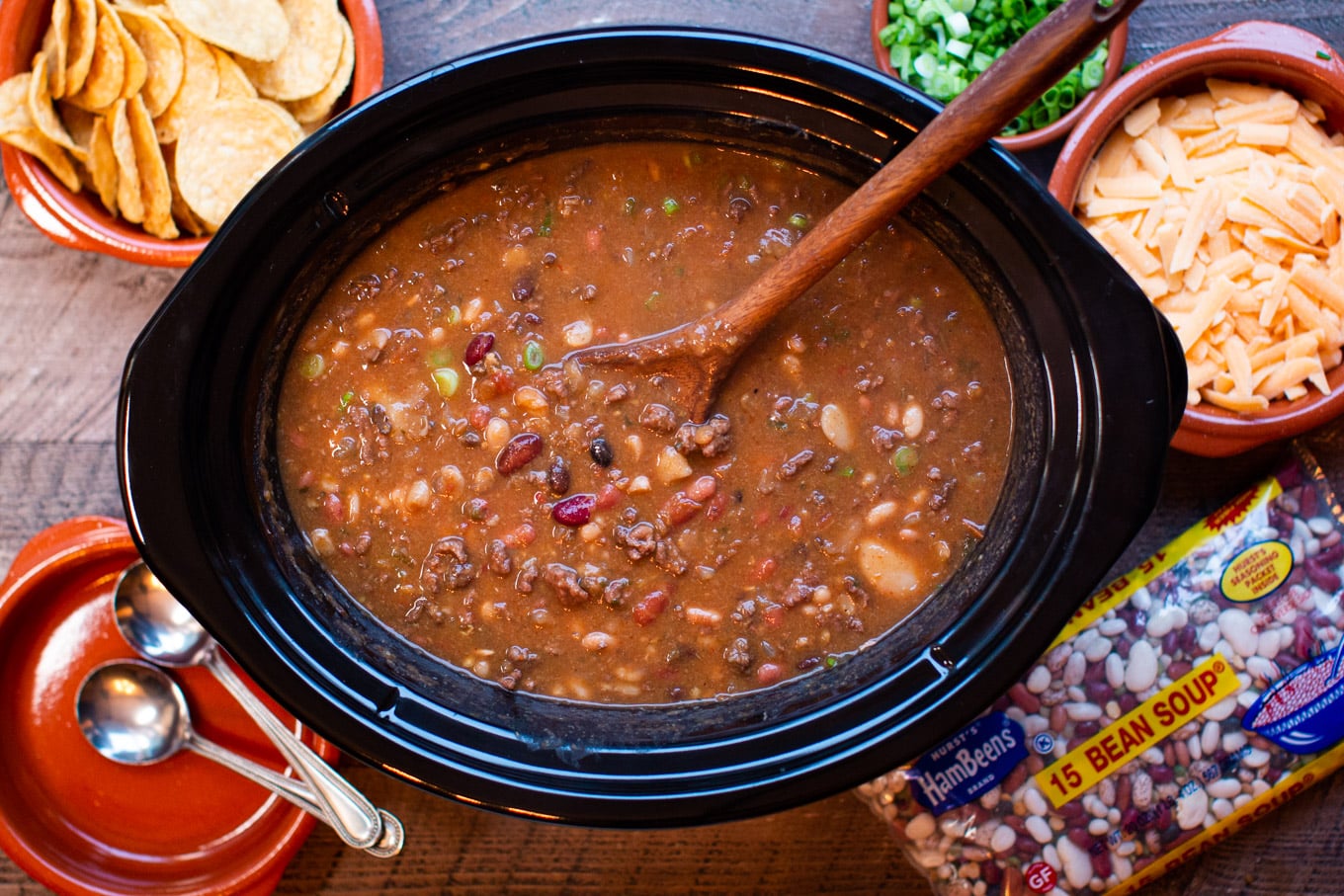 15 bean taco soup with spoon in it, chips and cheese on side