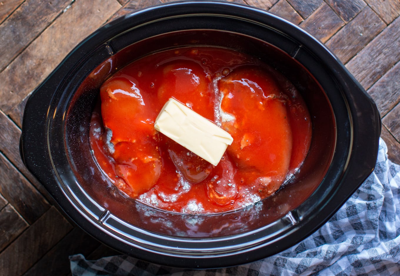 3 chicken breasts in slow cooker with ranch mix, buffalo sauce and a stick of butter on top.