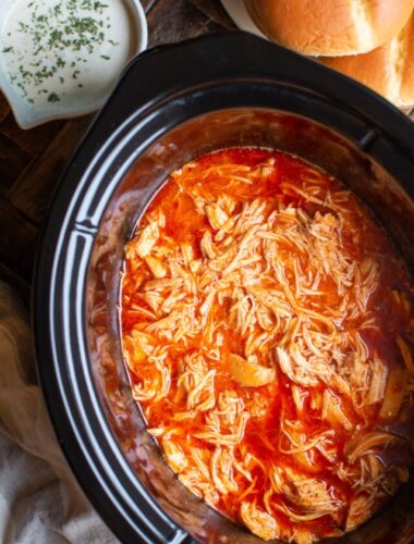 Cooked shredded buffalo chicken in a slow cooker.