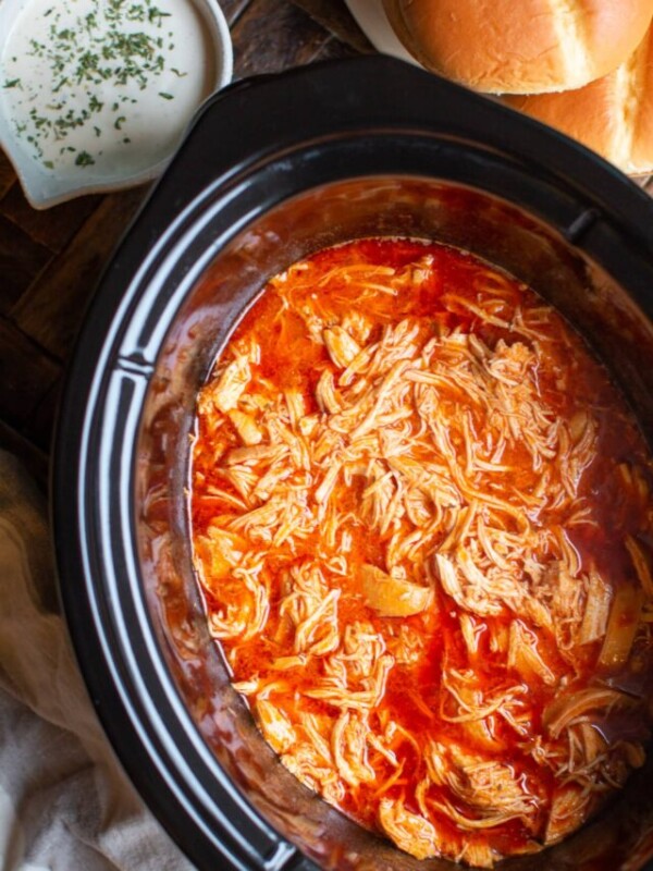 Cooked shredded buffalo chicken in a slow cooker.