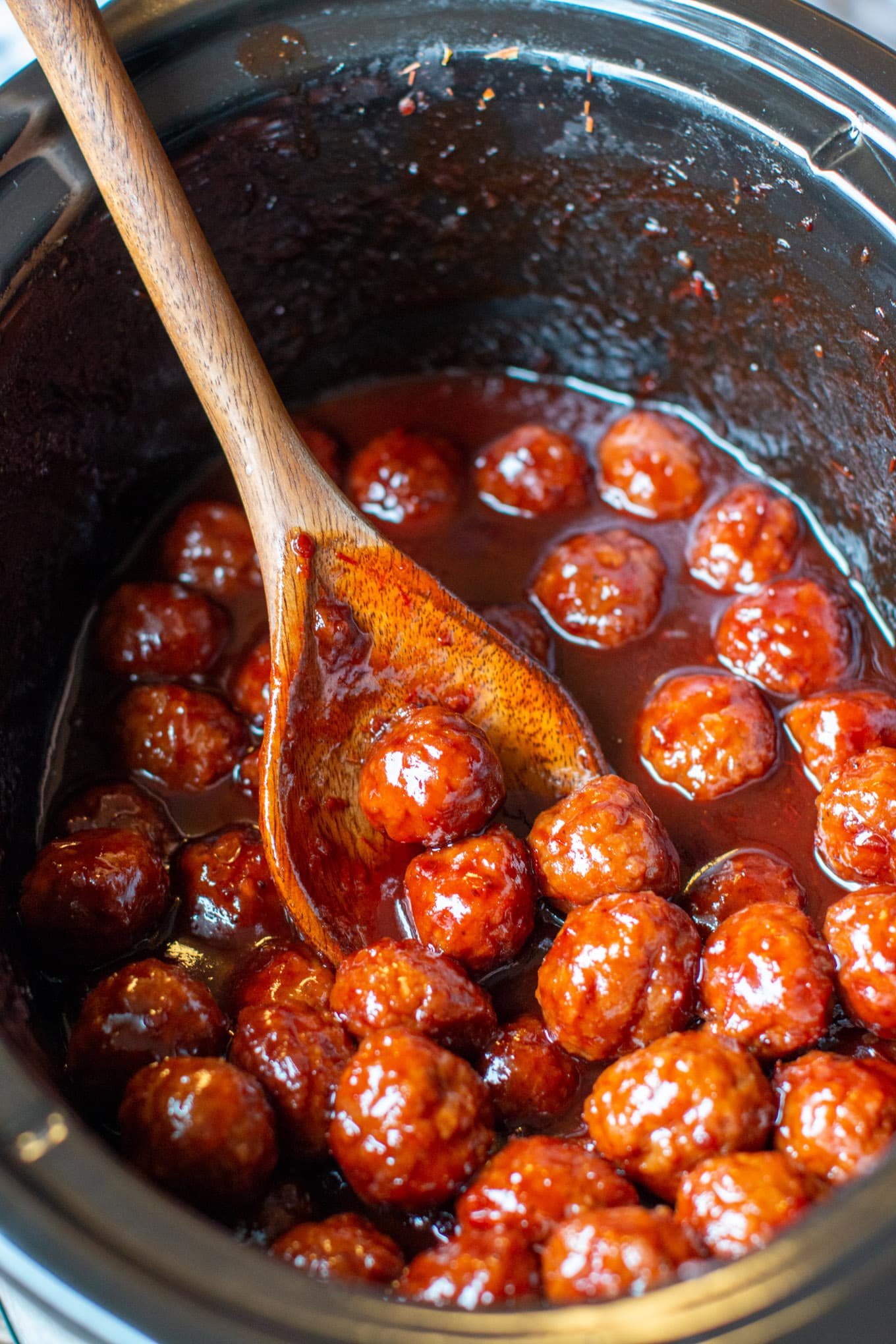 slow cooker full of grape jelly meatballs with spoon in them