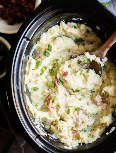 Colcannon potatoes with green onions on top. With wooden spoon in them.