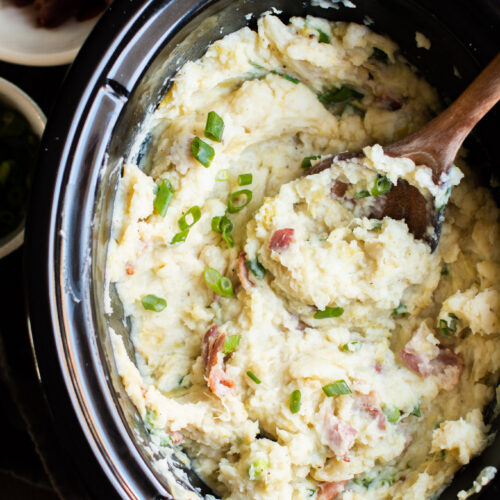 Colcannon potatoes with green onions on top. With wooden spoon in them.