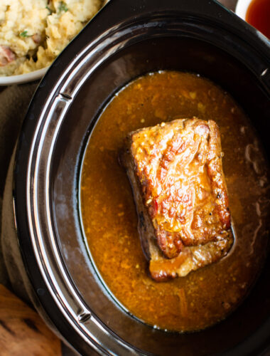 cooked corned beef brisket in sauce in slow cooker.