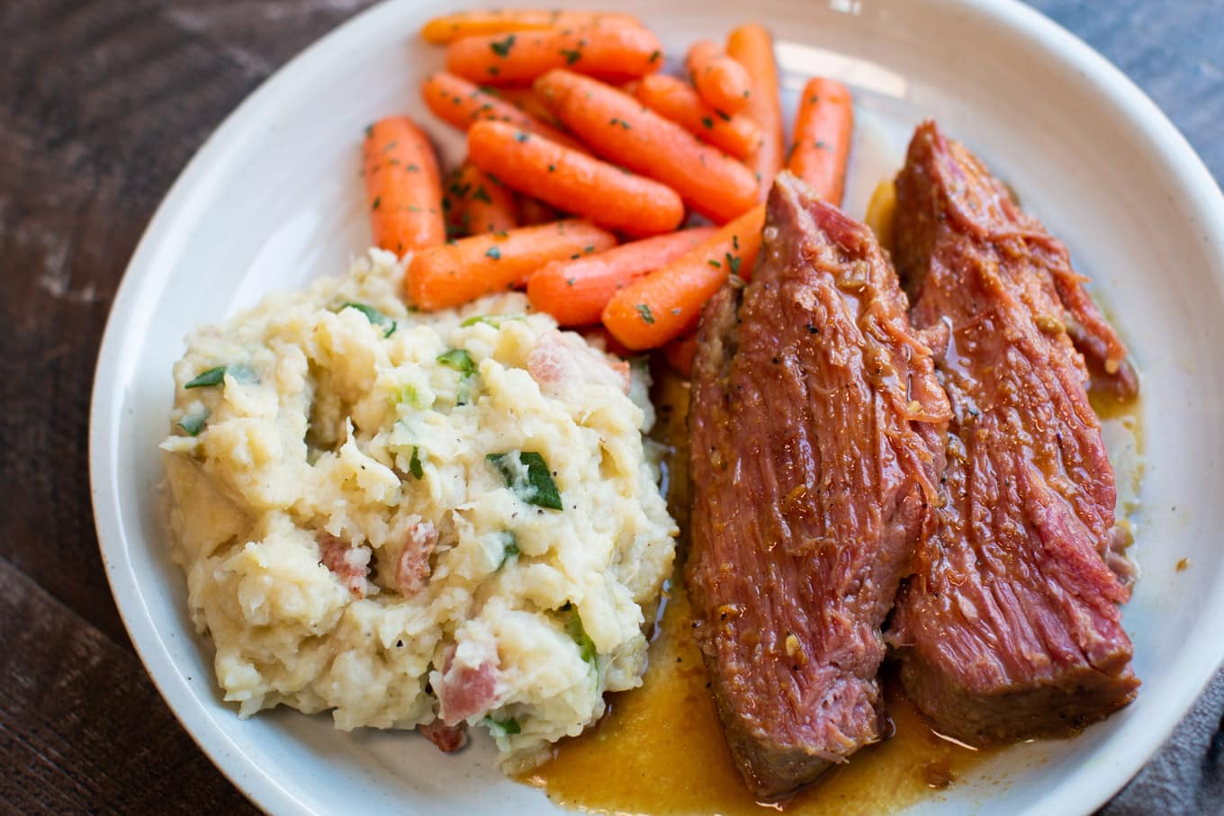 maple mustard corned beef with colcannon potatoes and carrots on a white plate