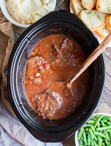 cooked swiss steaks with spatula in slow cooker