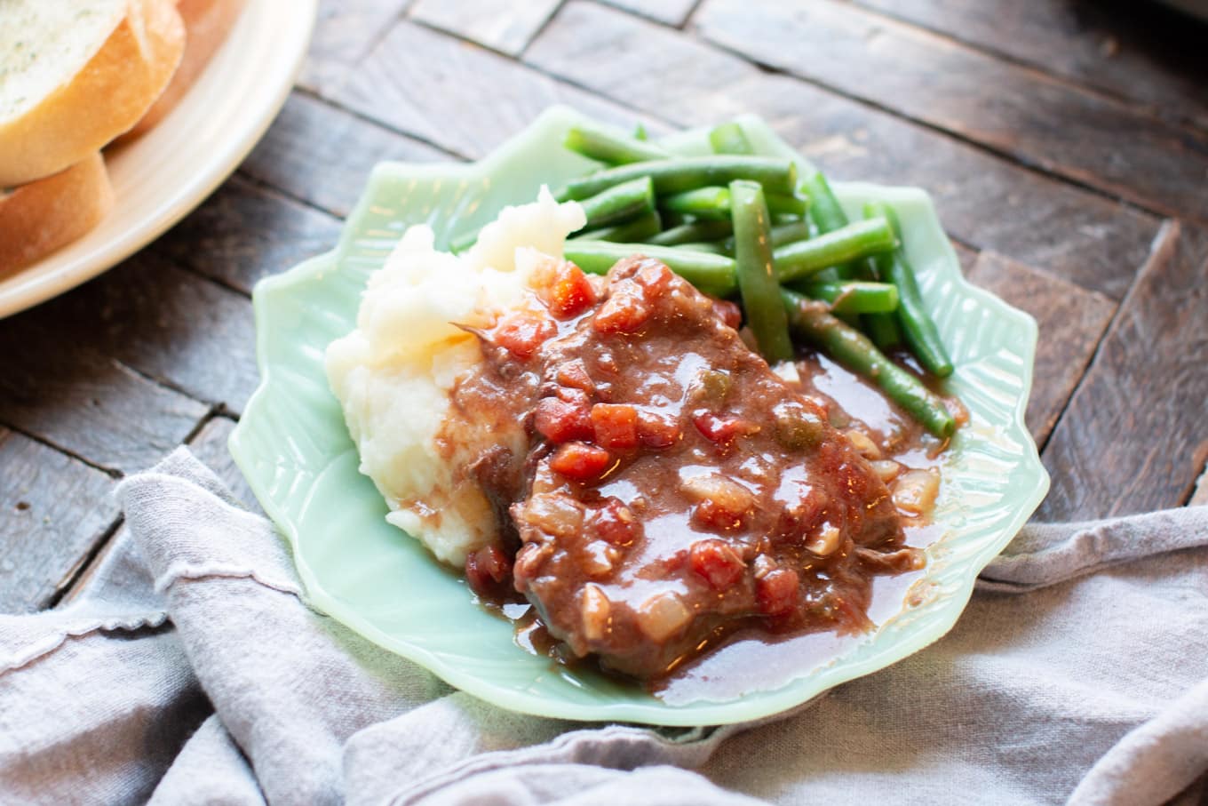 swiss steak plated with mashed potatoes and green beans