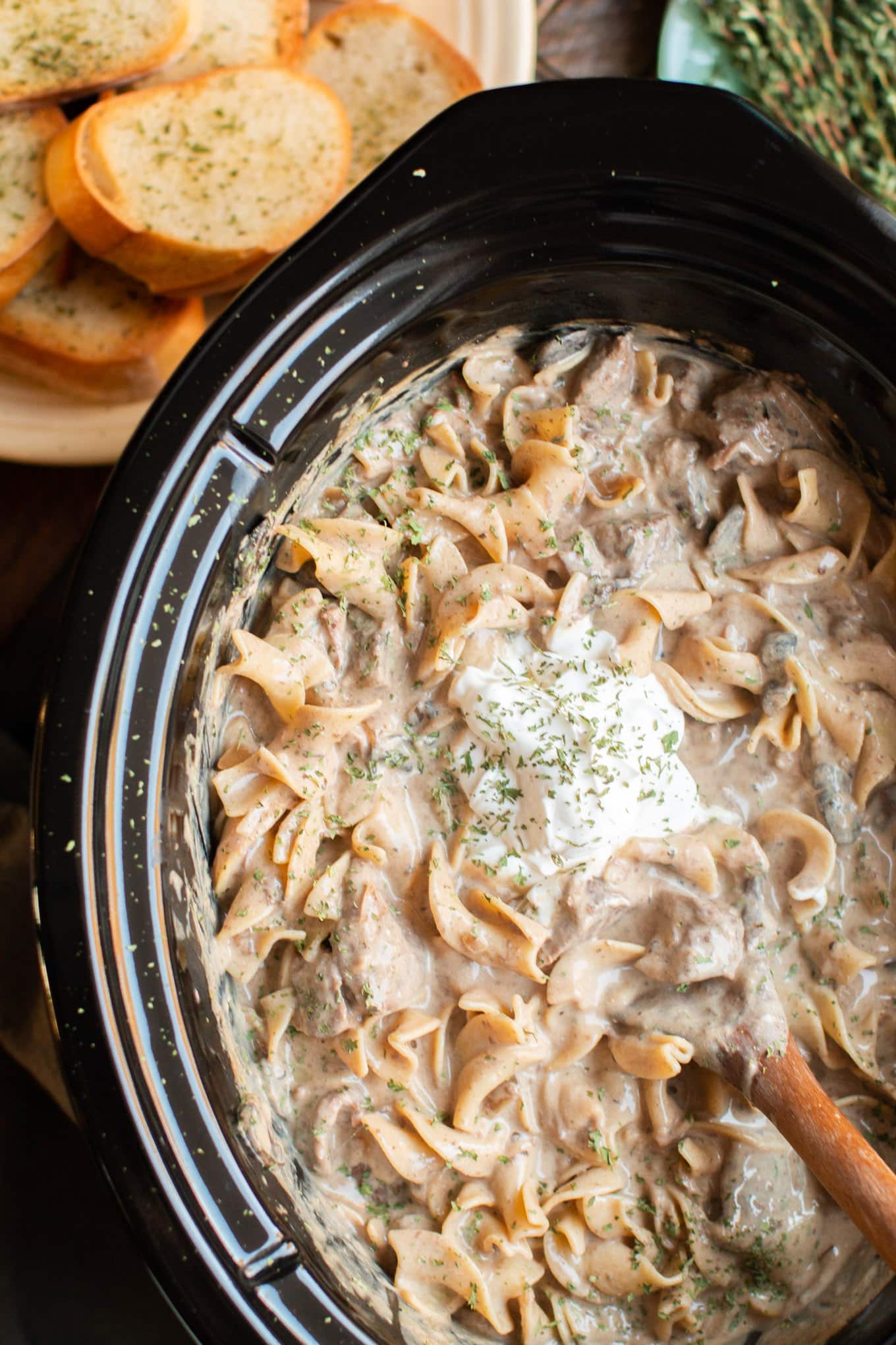 Slow Cooker Beef stroganoff in slow cooker, dollop of sour cream on top.