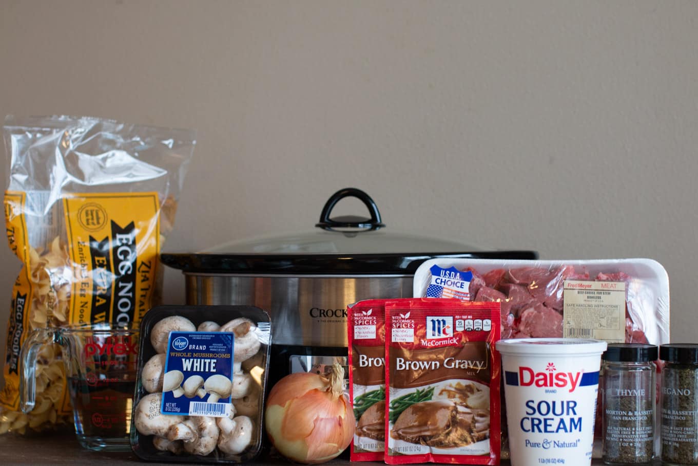 Ingredients with slow cooker: stew meat, veggies, brown gravy mix, sour cream, egg noodles, spices