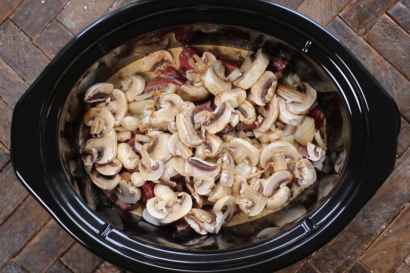 mushrooms and onions on top of beef stew meat.