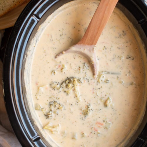 cooked broccoli cheese soup with wooden spoon in it.