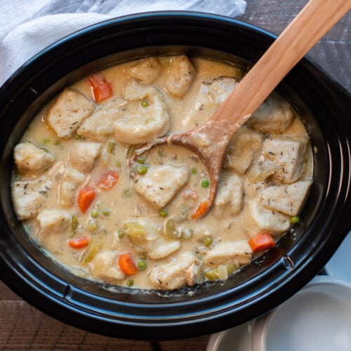 finished chicken and dumplings in slow cooker with spoon inside.