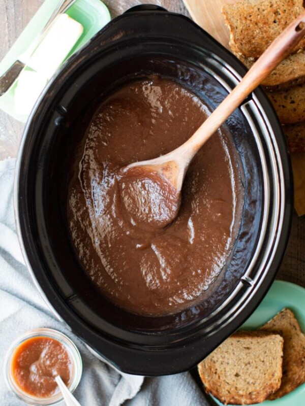 apple butter in slow cooker with wooden spoon.