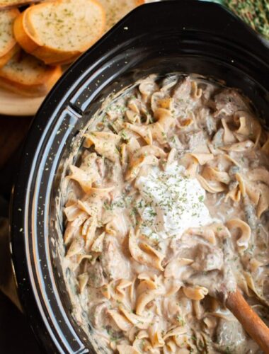 slow cooker beef stroganoff with sour cream on top.