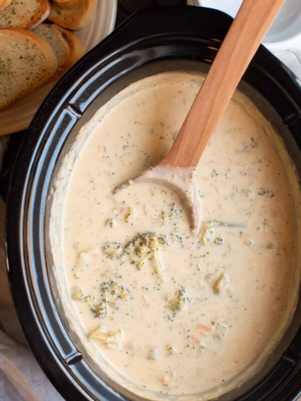 broccoli cheese soup with wooden spoon in slow cooker.