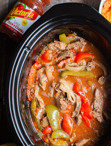 close up of beef strips, onion and bell peppers cooked in slow cooker.