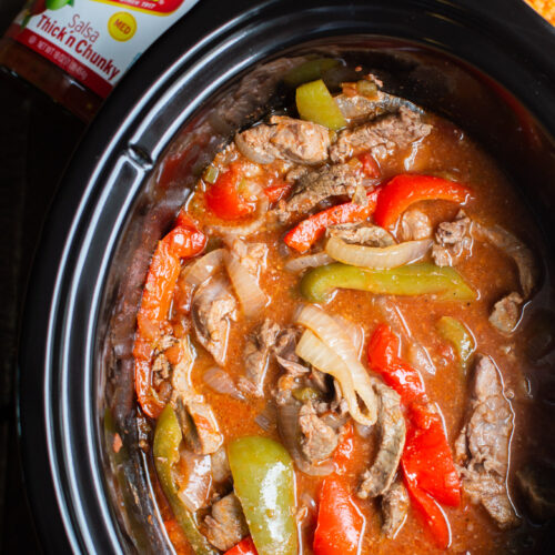 close up of beef strips, onion and bell peppers cooked in slow cooker.