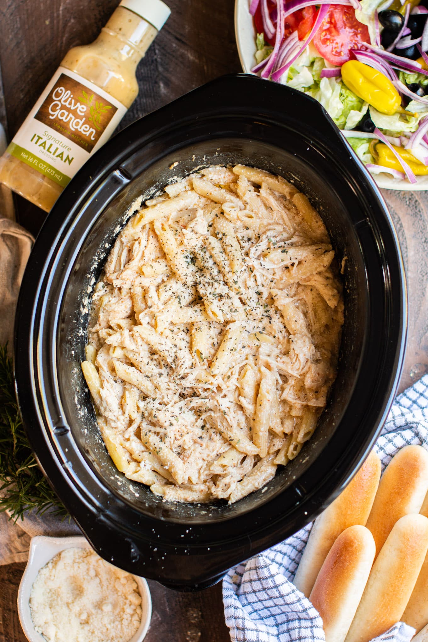 pasta in slow cooker with cheese on top. Breadsticks on the side.