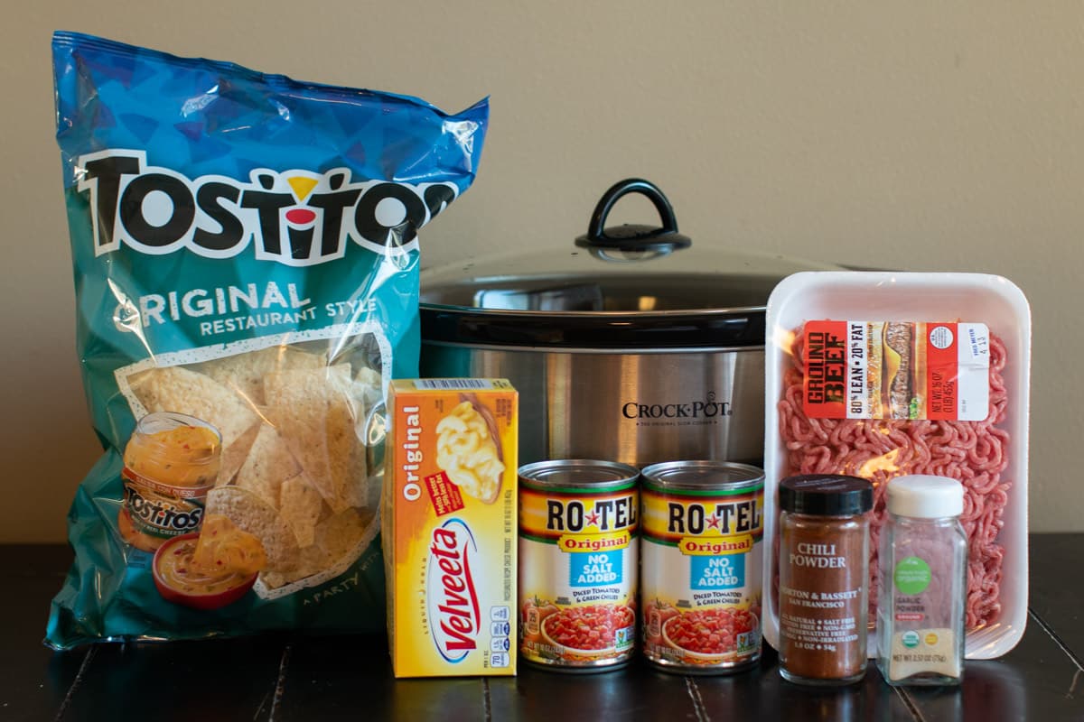 tostito chops, velveeta, 2 cans of rotel, package of ground beef and seasonings in front of slow cooker