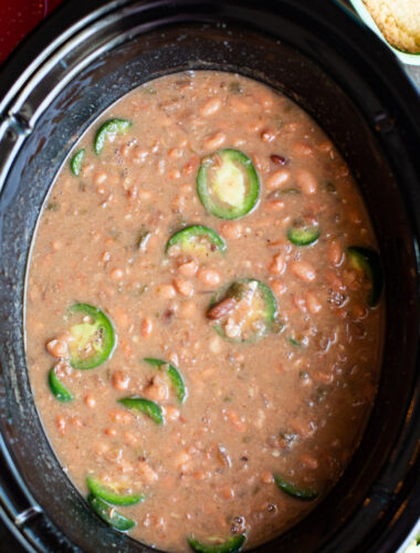 close up of spicy pinto beans with jalapenos on top.
