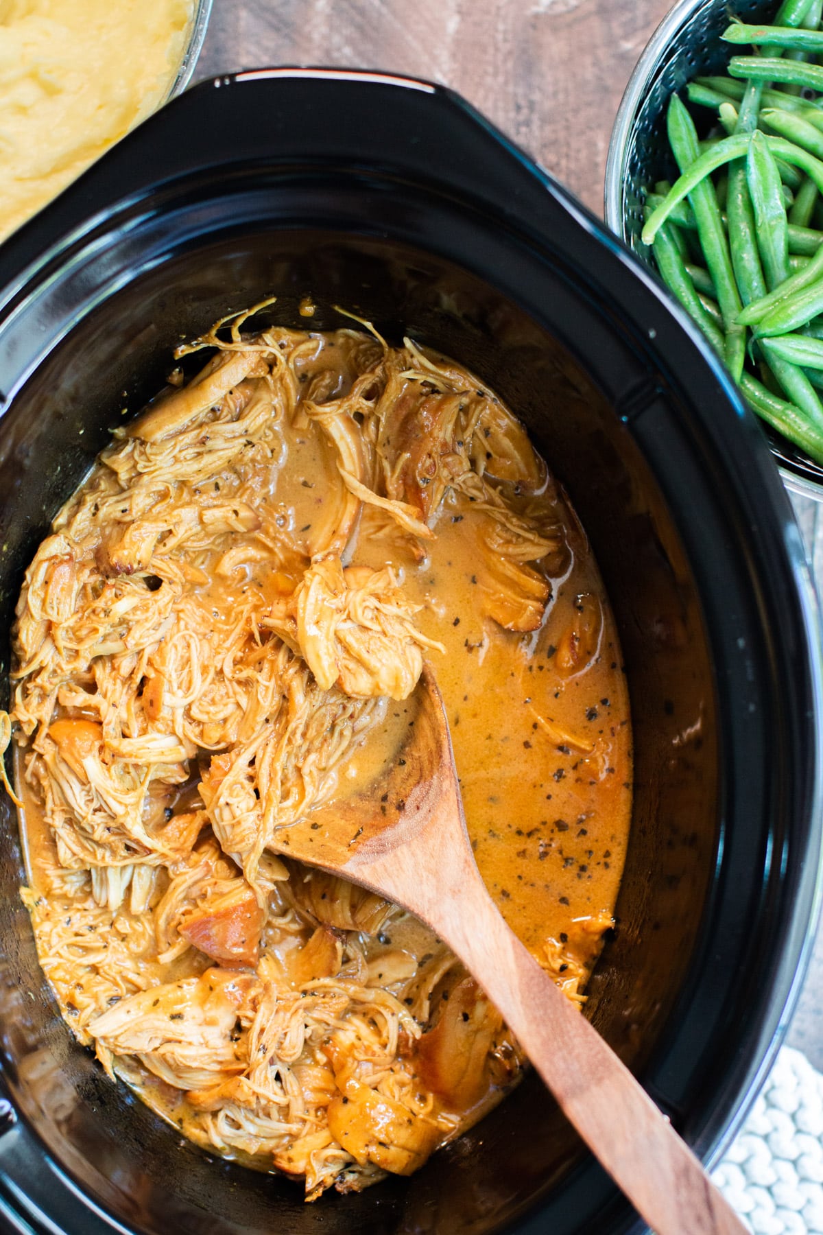close up of shredded creamy honey mustard chicken in a slow cooker.