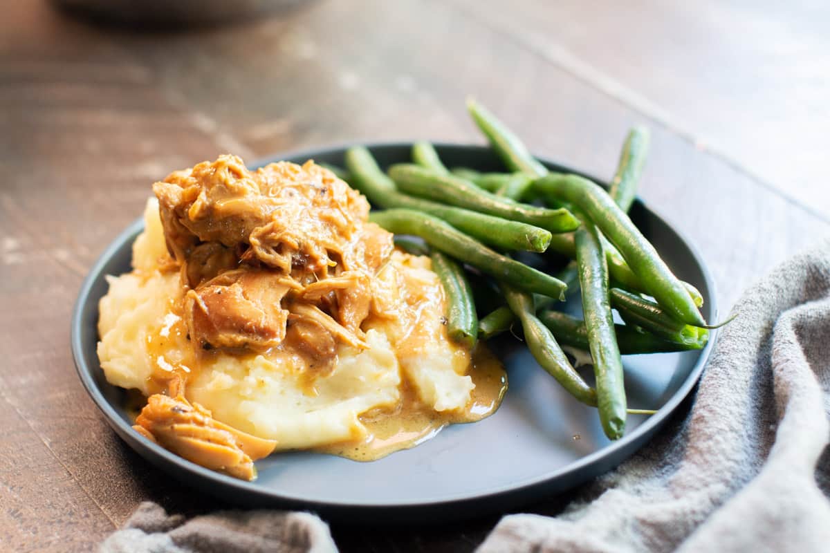 grey plate with mashed potatoes and shredded honey mustard chicken on top.