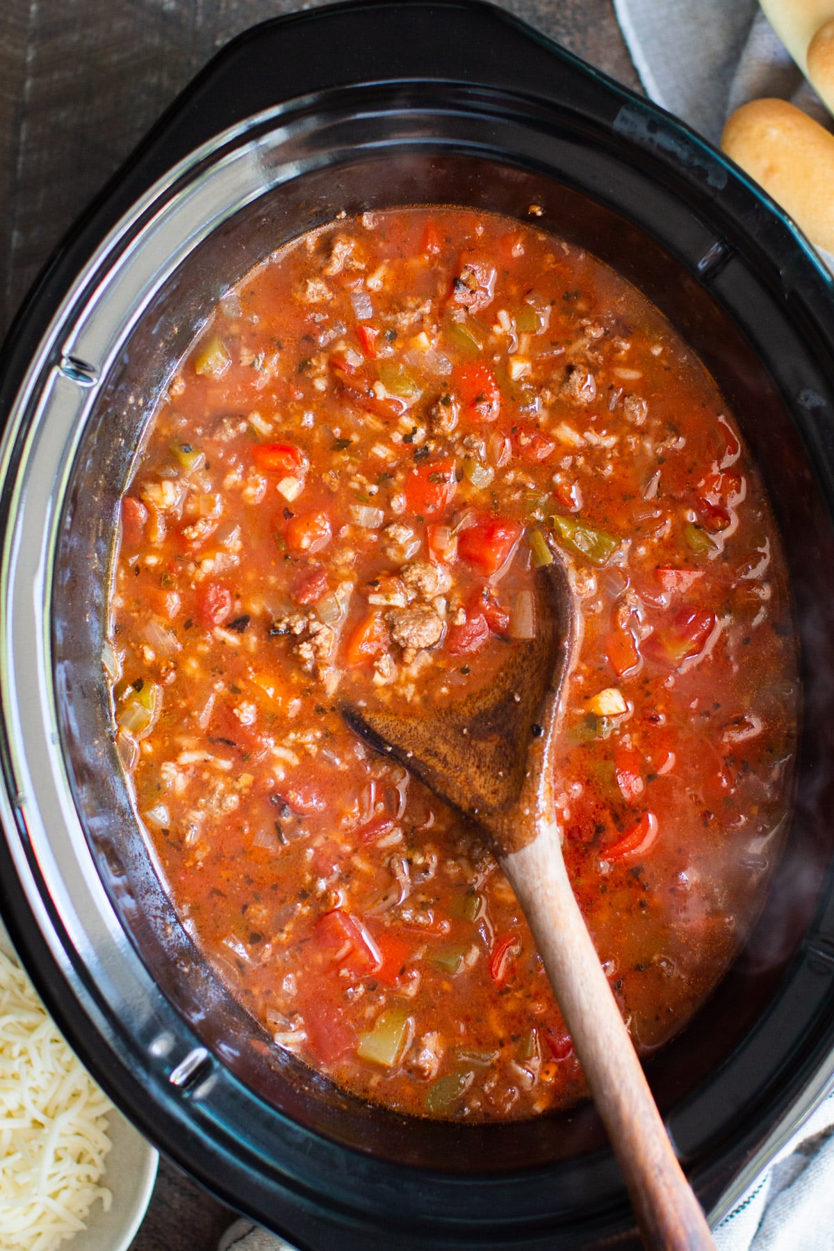 close up of stuffed pepper soup in the slow cooker with wooden spoon in it.