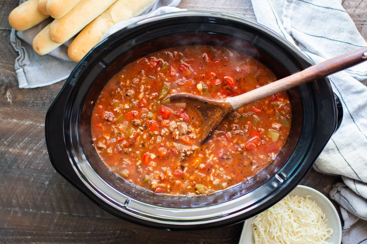 Finished cooking stuffed pepper soup with cheese and breadsticks on the side.