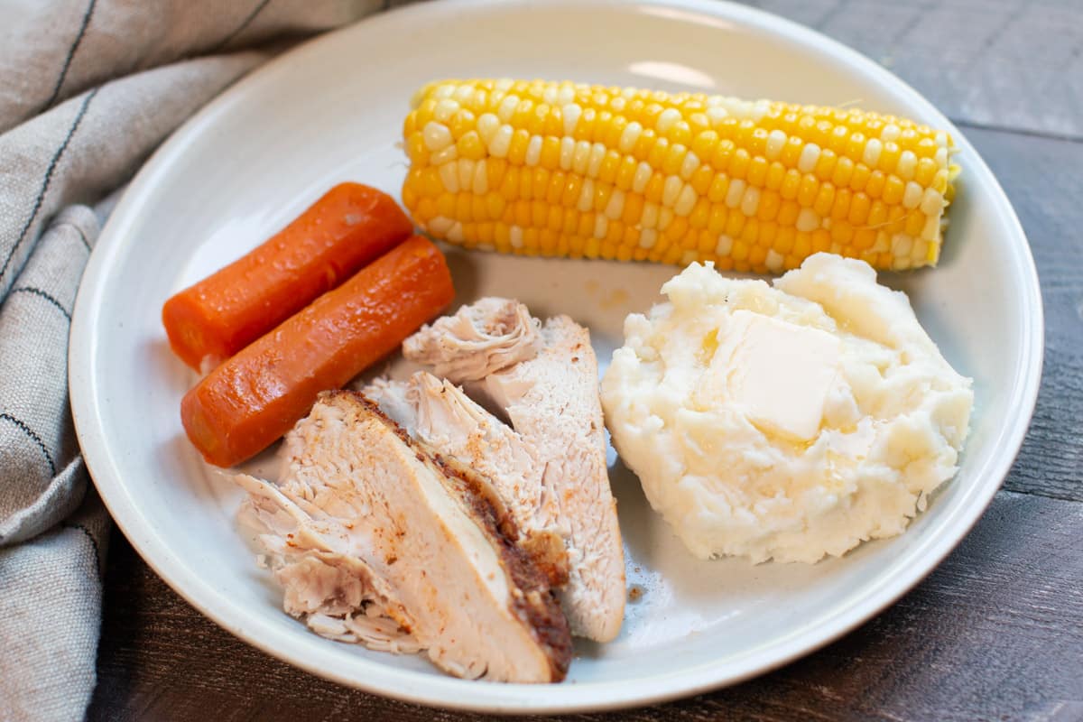 sliced chicken, mashed potatoes, corn and carrots on plate
