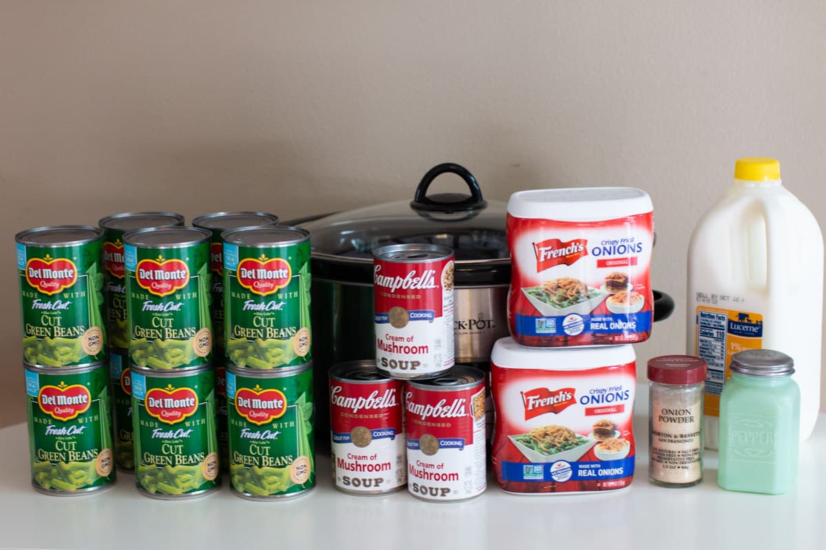 canned green beans, cream of mushroom soup, french fried onions, milk in front of slow cooker.