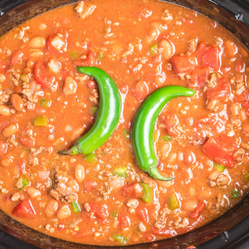 chili with 2 serrano peppers on top in slow cooker