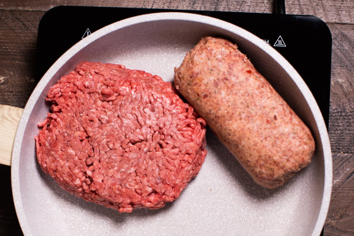skillet with a pound of ground beef and a pound of hot sausage