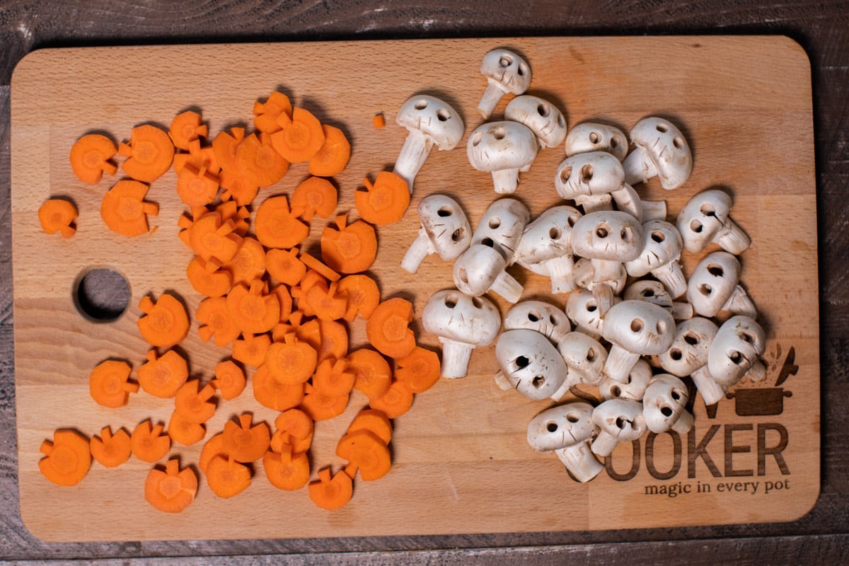cutting board with cut carrots shaped like pumpkins and mushrooms cut like skulls