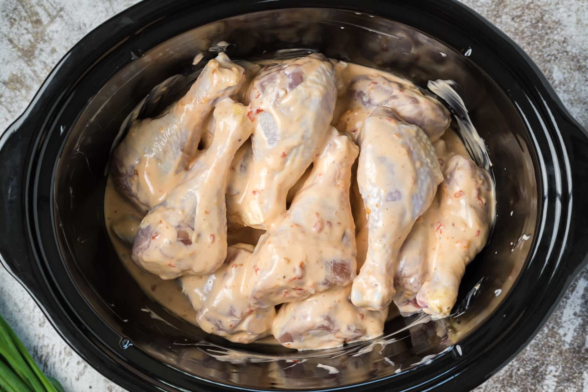 drumsticks in bang bang sauce in slow cooker before cooking.