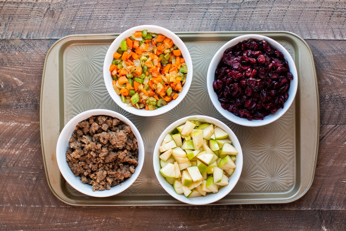 cooked sausage, cooked vegetables, dried cranberries, and sliced apple on tray