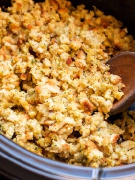 Close up of stove top stuffing in slow cooker with wooden spoon in it.