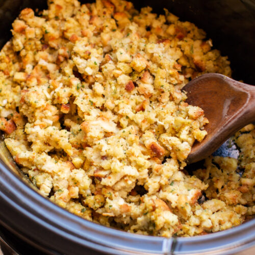 Close up of stove top stuffing in slow cooker with wooden spoon in it.