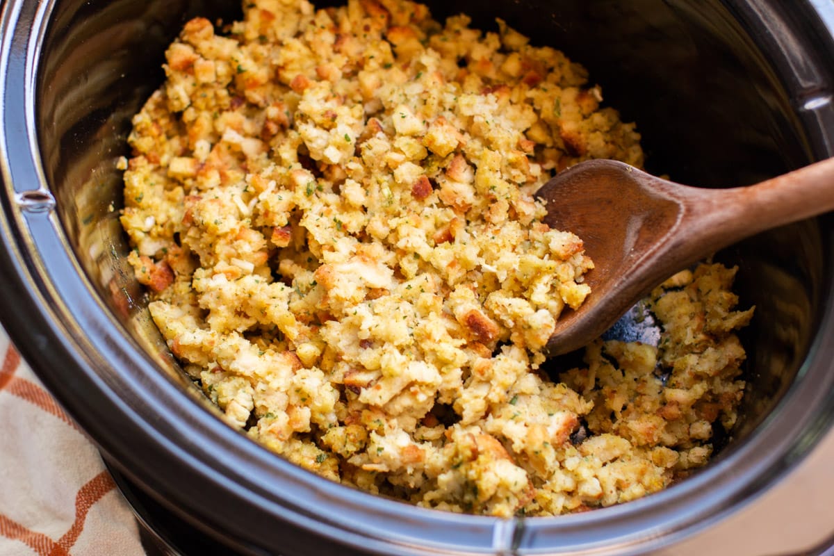 Close up of stove top stuffing in slow cooker with wooden spoon in it.